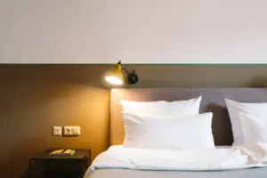 Hotelzimmer Kabinett im HENRI Hotel Garmisch-Partenkirchen Ein Bett mit weißen Kissen und einer Lampe im HENRI Hotel Garmisch-Partenkirchen.