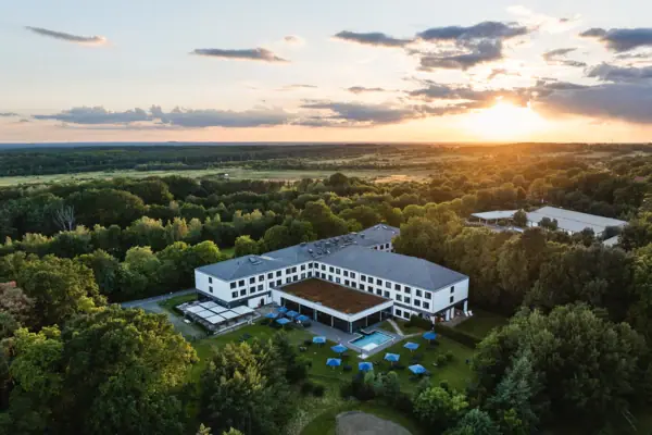 aja Bad Saarow Das aja Hotel in Bad Saarow mit einem Pool, umgeben von Bäumen.
