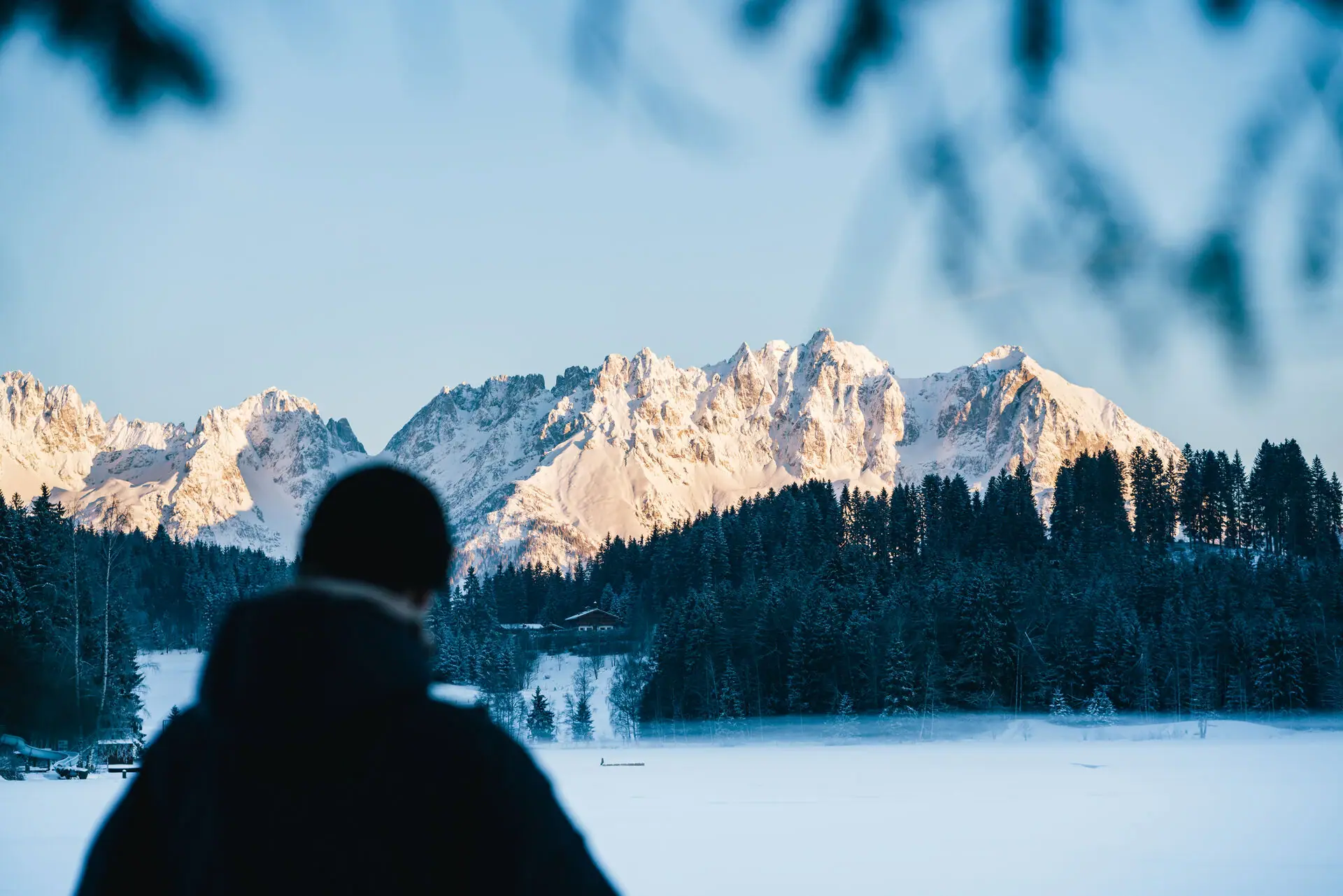 Kitzbüheler Alpen Eine Person steht vor einem schneebedeckten Berg.