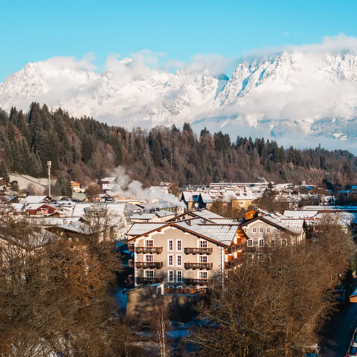 HENRI Hotel Kitzbühel Ort Kitzbühel im Winter mit schneebedeckten Bergen im Hintergrund.