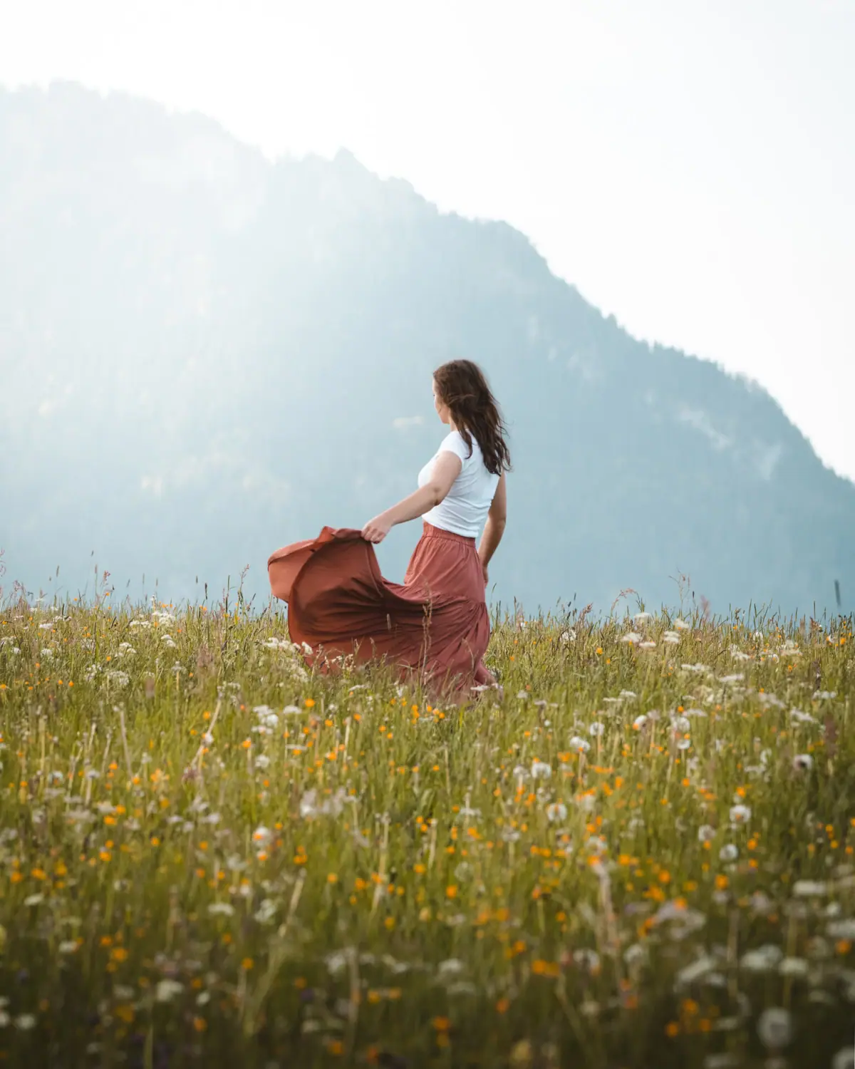 Blumenwiese vor einem Berg Eine Frau in einem Blumenfeld.