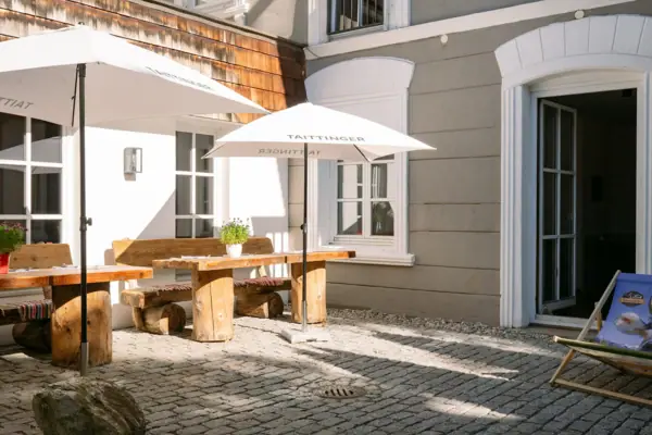 Außenbereich mit Sitzgelegenheiten im HENRI Kitzbühel Ein Patio mit Sonnenschirmen und Tischen.