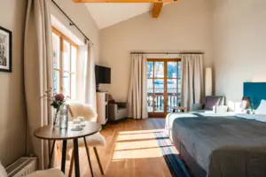 Schlafzimmer Geräumiges Zimmer mit Tisch und Doppelbett, lichtdurchfluetet mit vielen Fenstern.