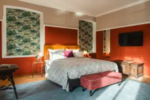 Salon Haus Kaiser HENRI Kitzbühel Das Hotelzimmer Salon im HENRI Hotel Kitzbühel mit roten Wänden und einem großen Bett.