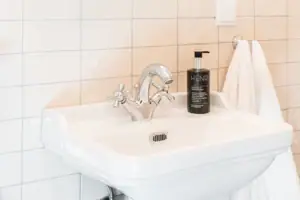 Badezimmer HENRI Kitzbühel Spiegel über einem Waschbecken mit einer Blume in einer Vase