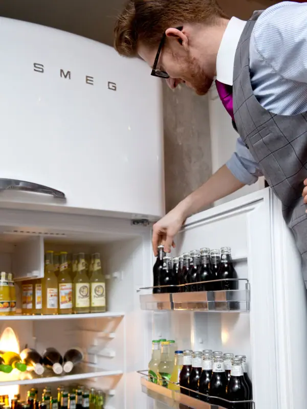 Getränkekühlschrank in Kontorküche Ein Mitarbeiter schaut in den Getränkekühlschrank