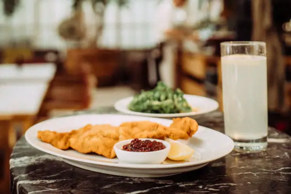 Wiener Schnitzel Ein Teller mit Essen und ein Glas Milch.