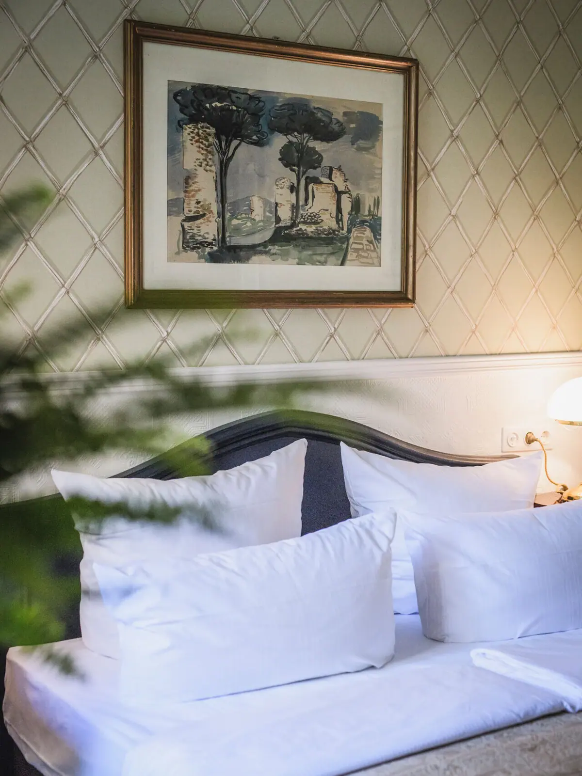 HENRI Berlin Anthroposophen-Zimmer Bett mit 2 Kissen vor einer antiken Tapete