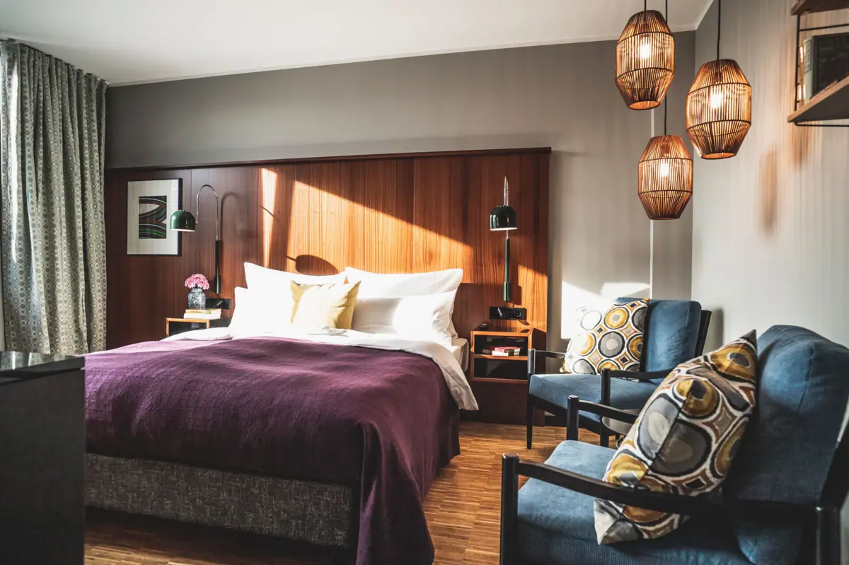 Zimmer im HENRI Hotel Düsseldorf Schlafzimmer mit einem Bett und zwei Stühlen.