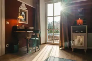 Salon Haus Kaiser HENRI Kitzbühel Das Hotelzimmer Salon im HENRI Hotel Kitzbühel mit roten Wänden, einem Schreibtisch und einem Fenster.