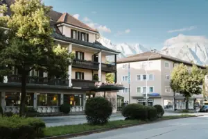 Außenansicht HENRI Hotel Garmisch-Partenkirchen Außenansicht HENRI Hotel Garmisch-Partenkirchen mit Bäumen und einer Straße.