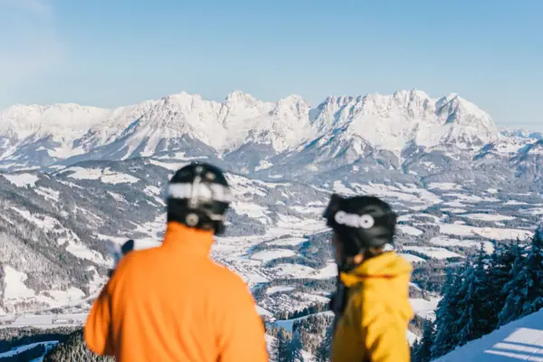 Tiroler Alpen im Schnee Zwei Personen mit Helmen blicken auf schneebedeckte Berge.