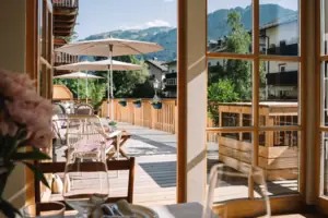 HENRI Kitzbühel Terrasse Terrasse mit Stühlen und Sonnenschirmen