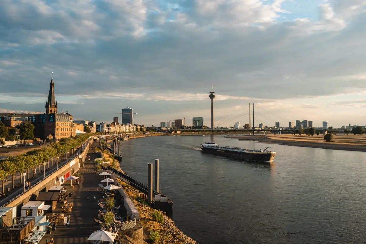 Rhein Promenade Ein Fluss mit einem Boot darauf.