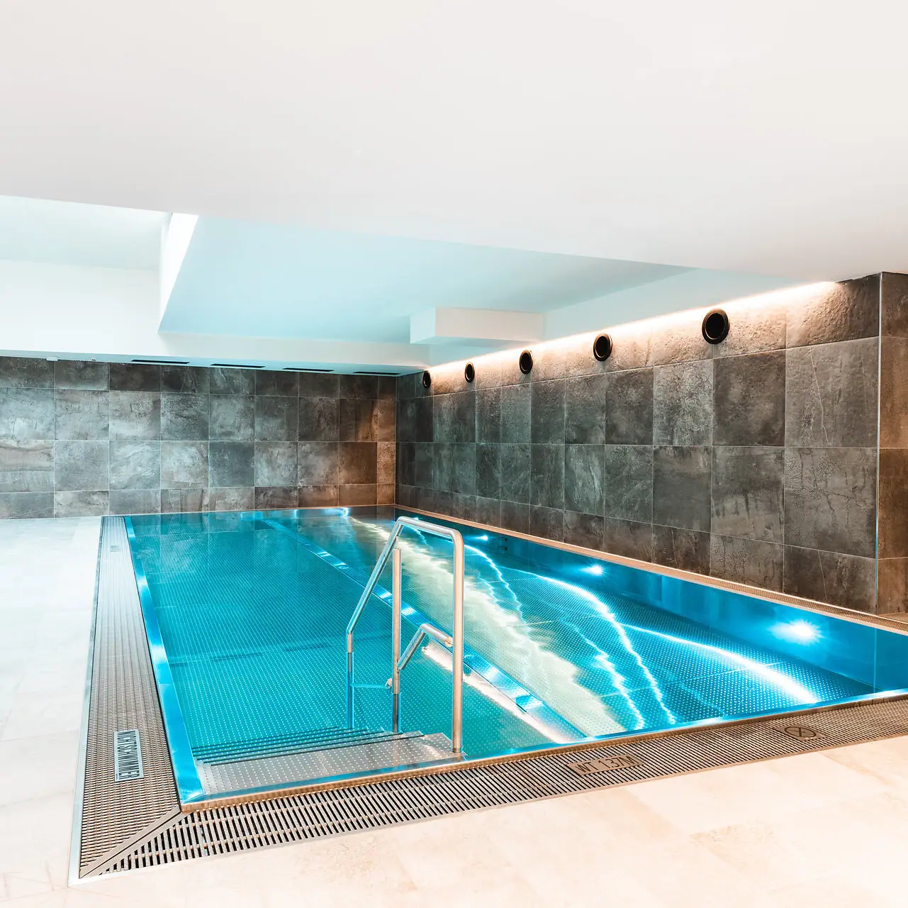 Indoor Schwimmbad im HENRI Kitzbühel Ein Hallenbad in einem Raum.