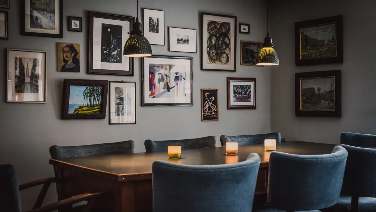 Großer Esstisch in Kontorküche Ein Tisch mit Kerzen und Stühlen in der Kontorküche mit Bildern an der Wand.