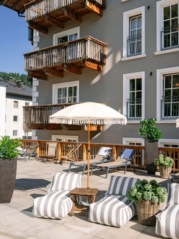 HENRI Kitzbühel Terrasse Terrasse mit Stühlen und Sonnenschirm