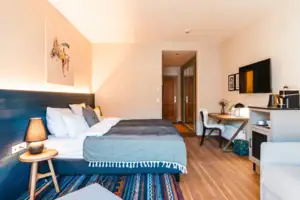 L-Studio Haus Ache HENRI Hotel Kitzbühel Schlafzimmer mit einem Bett und einem Schreibtisch.