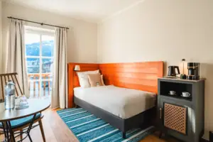 Zimmer mit Bett Einzelbett mit Terrassentür und kleinem Tisch.