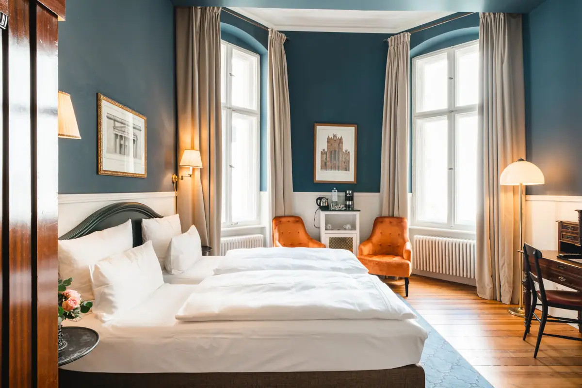 HENRI Berlin Zimmer Blau Ein Zimmer mit zwei Betten und einem Stuhl.