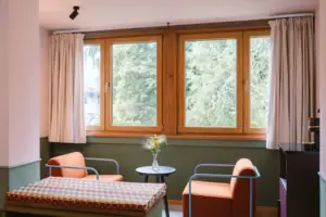 Hotelzimmer im HENRI Hotel Garmisch-Partenkirchen Eine Sitzecke mit zwei Sesseln vor einem Fenster in dem Hotelzimmer Chambre im HENRI Hotel Garmisch-Partenkirchen.