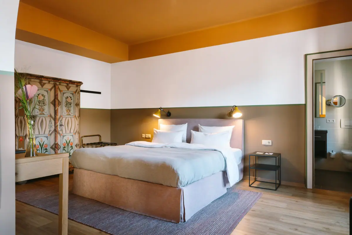 Hotelzimmer im HENRI Garmisch-Partenkirchen Ein Bett in einem Hotelzimmer mit stilvollem Interieurdesign.