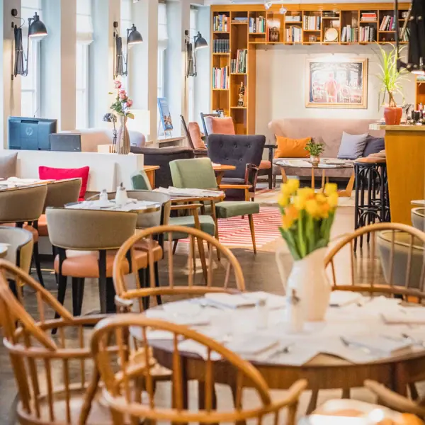 Ess- und Loungebereich im HENRI Hamburg Tische, Stühle und im Hintergrund ein gemütlicher Loungebereich