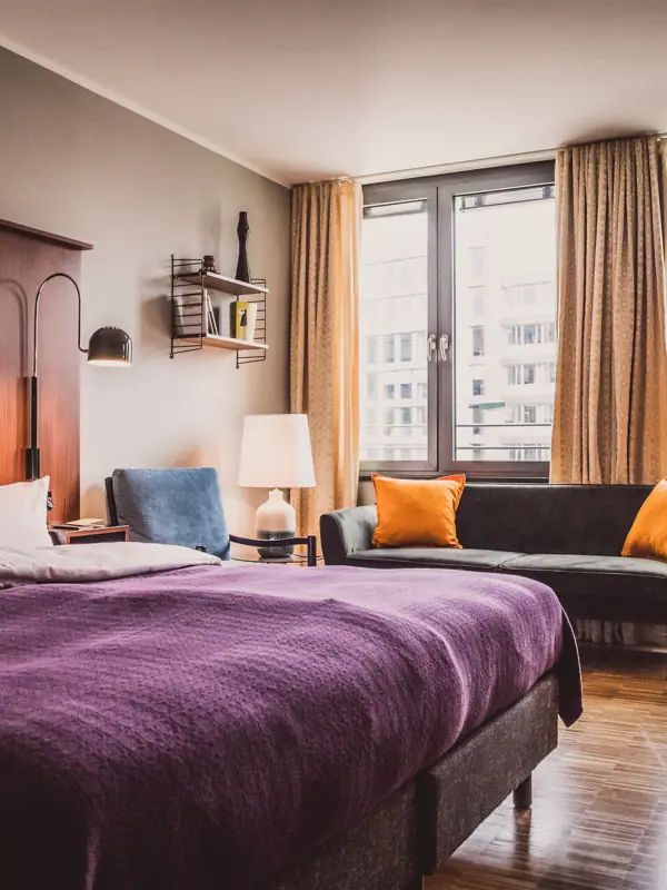 HENRI Düsseldorf Schlafzimmer mit lila Bett und Couch.