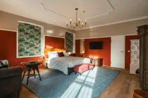 Salon Haus Kaiser HENRI Kitzbühel Das Hotelzimmer Salon im HENRI Hotel Kitzbühel mit roten Wänden und einem großen Bett.