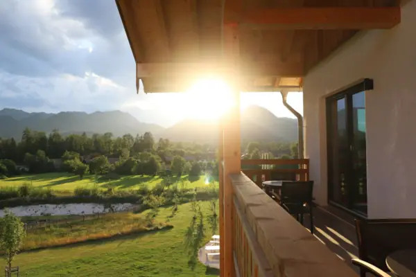 aja Hotel Ruhpolding Sonne scheint durch die Bäume auf eine Veranda Balkones im aja Riuhpolding.