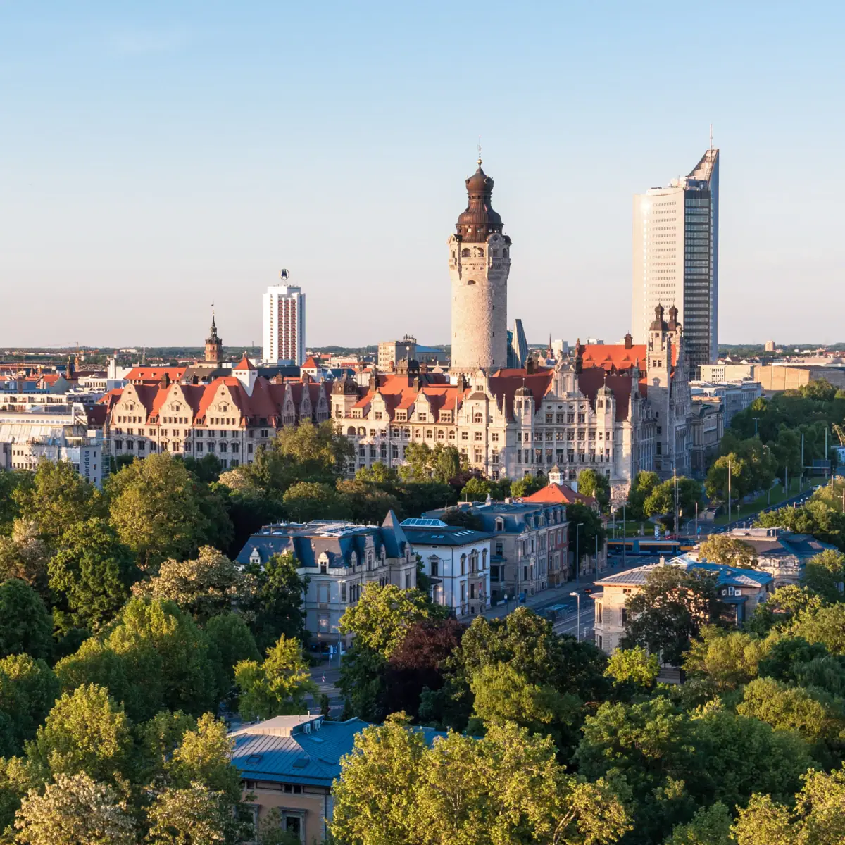 Leipzig Skyline Die Skyline von Leipzig mit Bäumen und Gebäuden im Morgenlicht.
