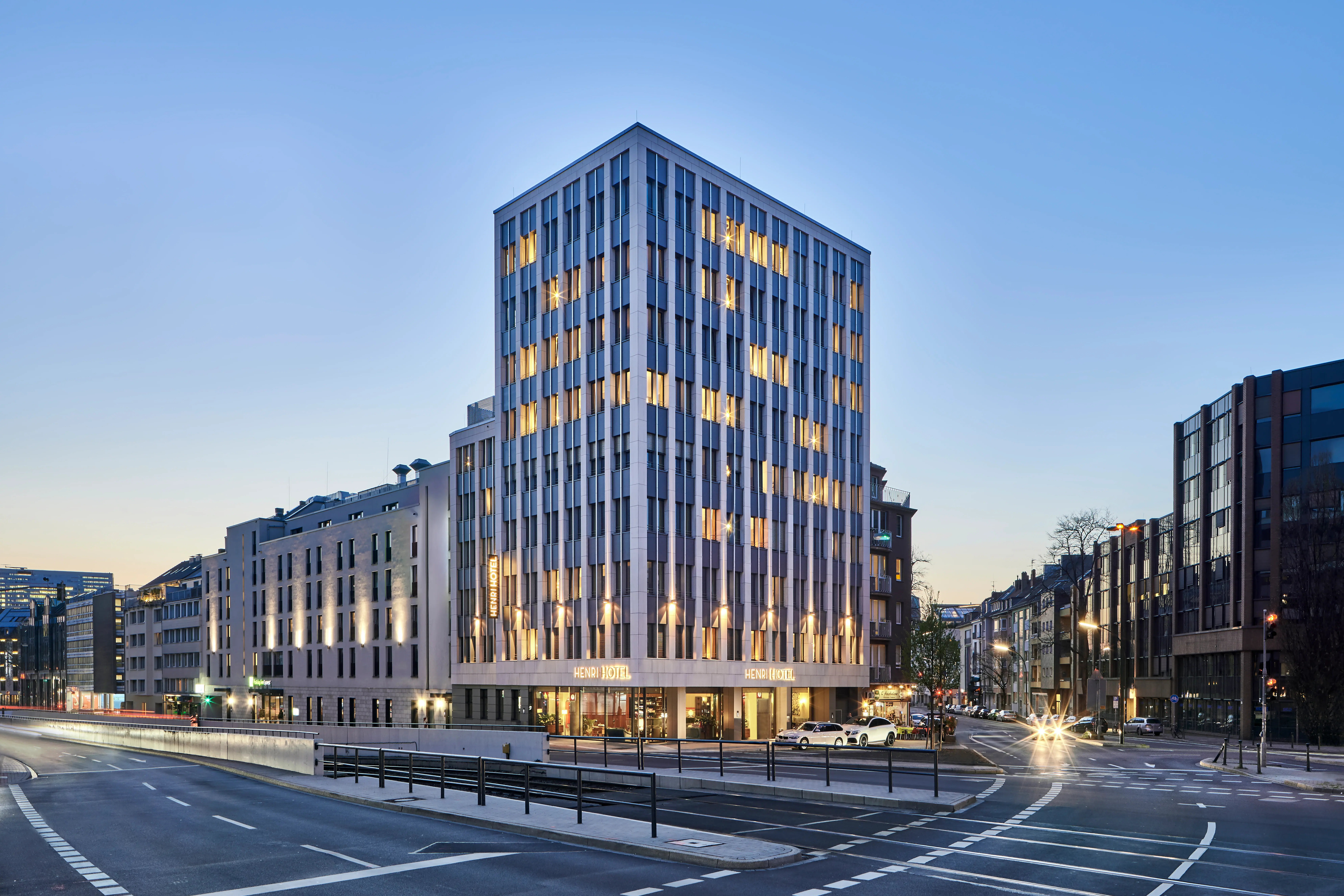 Ein beleuchtetes Hochhaus in einer städtischen Umgebung bei Nacht.
