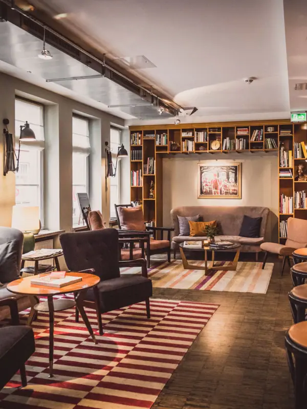 Loungebereich im HENRI Hotel Hamburg Sitzgruppen aus Sesseln, Tischen und einem Sofa im Loungebereich.