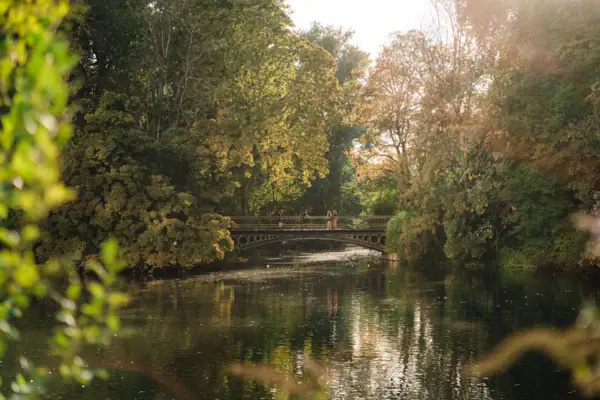 Park Brücke über ein Gewässer mit Bäumen im Herbst.