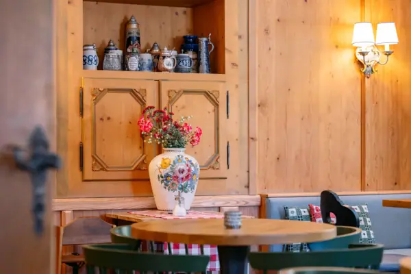 Klausner Stube im HENRI Hotel Kitzbühel Ein Tisch mit einer Vase voller Blumen darauf.
