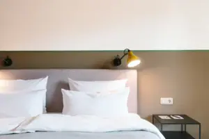 Hotelzimmer im HENRI Hotel Garmisch-Partenkirchen Ein Bett mit weißen Kissen vor einer zwei-farbigen Wand im HENRI Hotel Garmisch-Partenkirchen.