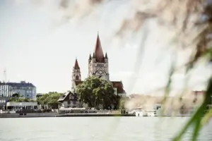 Kirche Ein Gebäude mit einem Uhrturm und Bäumen am Wasser.
