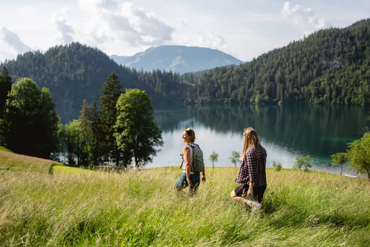 Wanderung am See entlang Zwei Personen stehen in einem grasbewachsenen Feld an einem See.