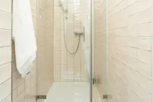 Badezimmer HENRI Kitzbühel Dusche mit Glastür und Fliesen.