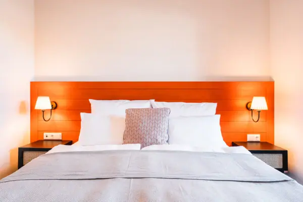 Bett Ein Bett mit Kissen und einer Lampe auf dem Nachttisch.